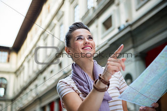 Portrait of happy young woman with map pointing near uffizi gall