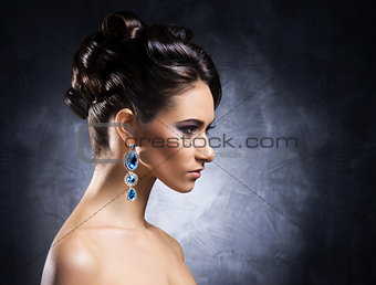 Young, beautiful and rich woman in jewels of platinum and stones over luxury background 