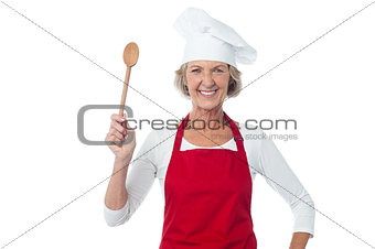 Happy aged chef holding wooden spoon