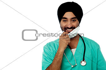 Smiling male doctor removing surgical mask