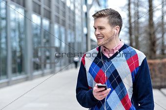 Smiling man listens music in a street