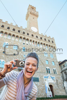Portrait of smiling young woman with photo camera in front of pa