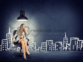 Woman wearing jacket, blouse sitting with legs crossed. Background sketch of buildings