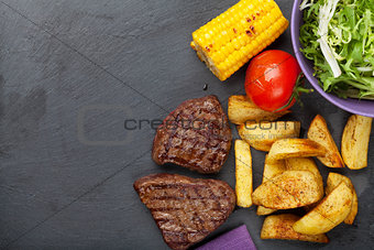 Steak with grilled potato, corn, salad and tomato