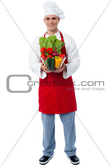 Chef holding glass bowl full of vegetables