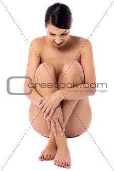 Young naked woman sitting, studio shot