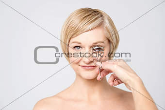 Woman using eye lash curler