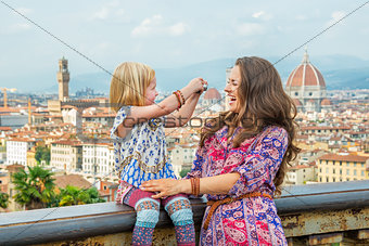 Happy baby girl taking photo of mother against panoramic view of
