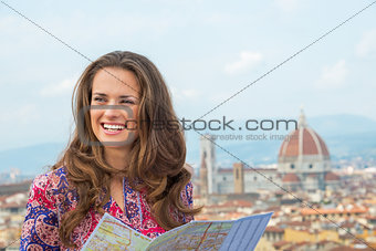 Portrait of happy young woman with map against panoramic view of