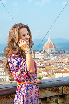Happy young woman talking cell phone against panoramic view of f