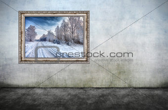 Old wooden frame with beautiful winter landscape on dirty wall