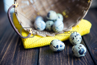 Easter quail eggs in the basket on rustic wooden background. Selective soft focus