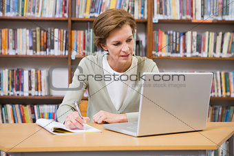 Teacher writing on notepad at library