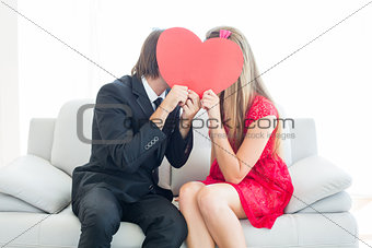 Cute geeky couple kissing and holding heart over faces