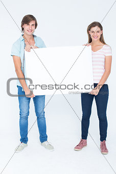 Hipster couple holding poster and smiling at camera