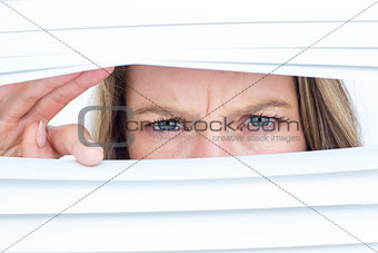Woman peering through roller blind