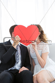 Couple kissing behind heart card
