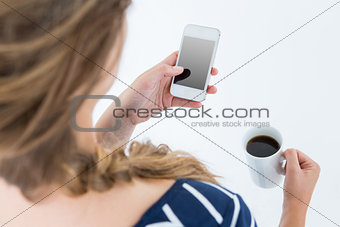 Woman using smartphone and holding mug