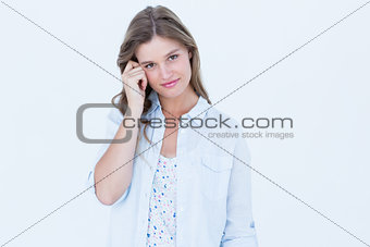 Woman smiling at camera with finger on temple