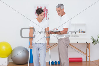 Doctor showing clipboard to his patient with crutch