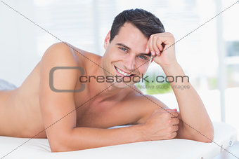 Smiling patient lying on massage table and looking at camera