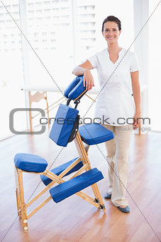Smiling therapist standing with massage chair