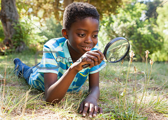 Cute little boy looking through magnifying glass