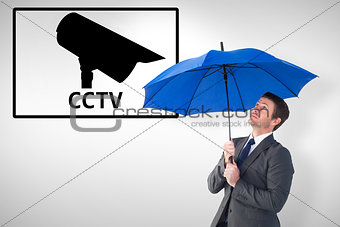 Composite image of businessman sheltering under blue umbrella