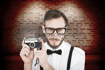 Composite image of geeky hipster holding a retro camera