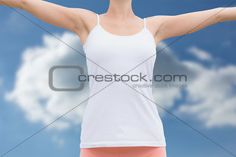 Composite image of beautiful woman with arms raised against the sky