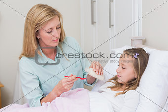 Mother giving her daughter cough medicine