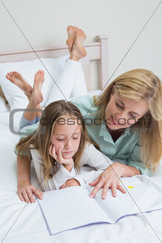 Happy mother and daughter reading a book
