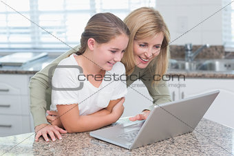 Happy mother and daughter using laptop together