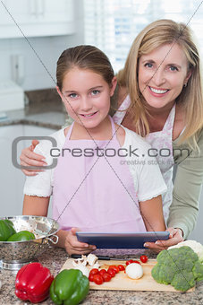 Mother and daughter cooking together with tablet pc