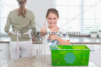 Little girl holding recycling bottles with thumbs up