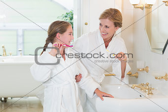 Happy mother and daughter brushing teeth together