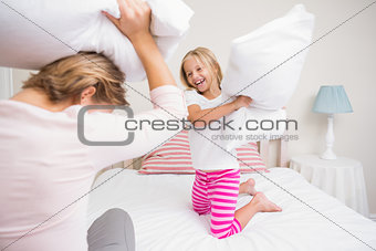 Mother and daughter having pillow fight