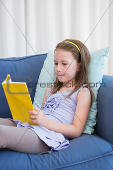 Little girl reading on couch