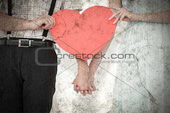 Composite image of hipster couple holding heart card