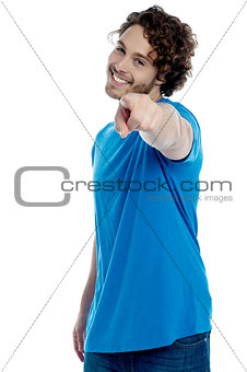 Handsome young man pointing towards camera