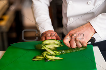 Chef chopping leek over green carving board