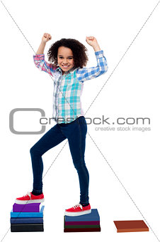 Active girl kid climbing on notebooks