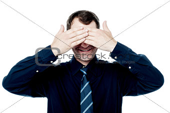 Smiling businessman put his hands over eyes