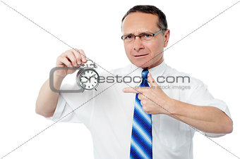 Smiling businessman holding an alarm clock
