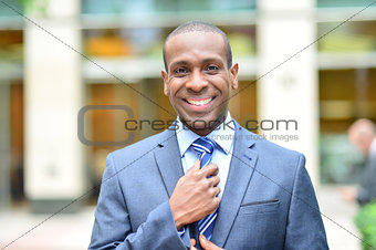 Smiling businessman adjusting his tie