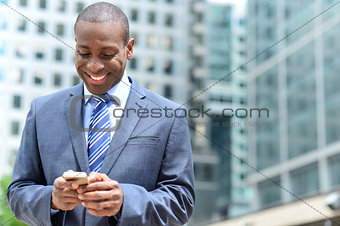 Smiling businessman using his smartphone