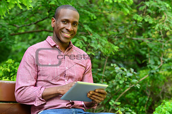 Happy guy using his tablet pc, outdoors
