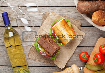 Two sandwiches with salad, ham, cheese and tomatoes with white w