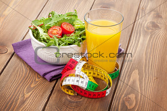 Healthy salad, orange glass and tape measure