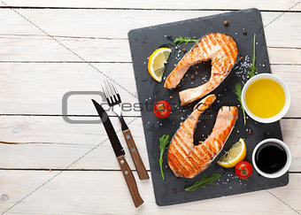 Grilled salmon, salad and condiments on wooden table
